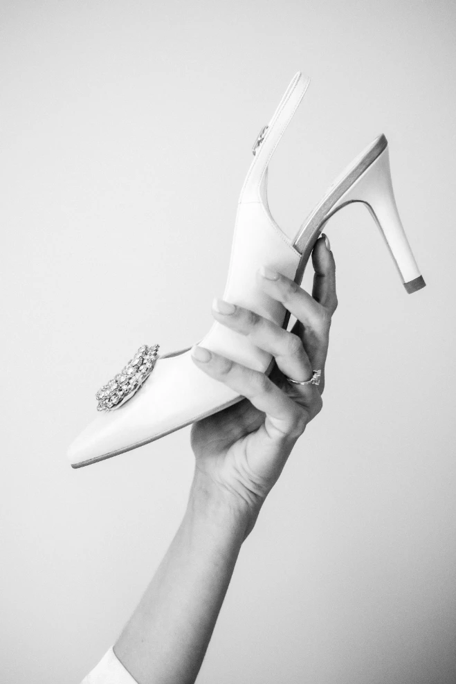 Mano de novia con anillo sujetando un tacón en blanco y negro - Fotógrafo de bodas en Málaga