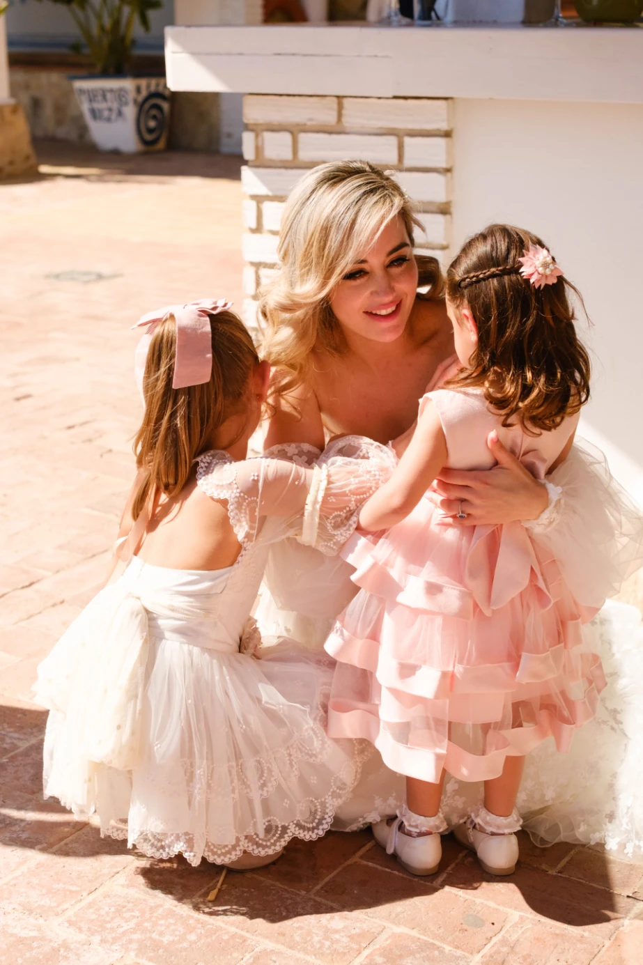 La novia, abrazandoa a las mas Damas de Honor mas pequeñas de la boda.